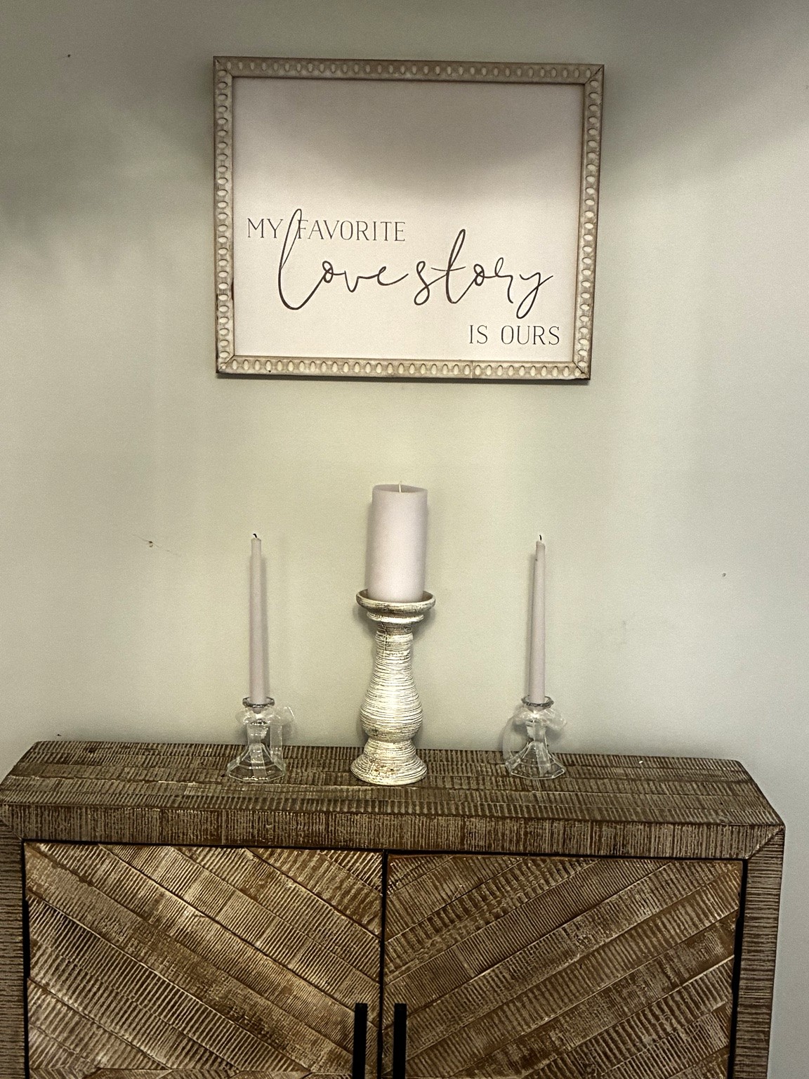 Unity candles on a wooden cabinet beneath a My Favorite Love Story Is Ours sign
